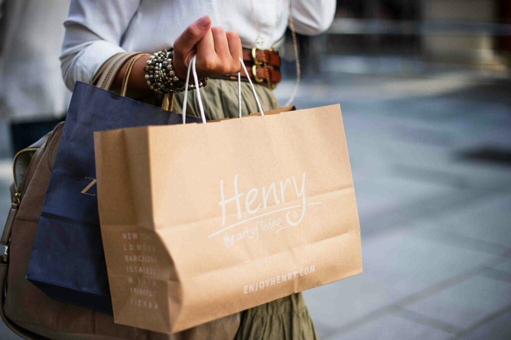 fidéliser ses clients, permet de les voir plus souvent et augmenter leur panier moyen. sur la photo, une femme tiens dans sa mains plusieurs sac de shopping